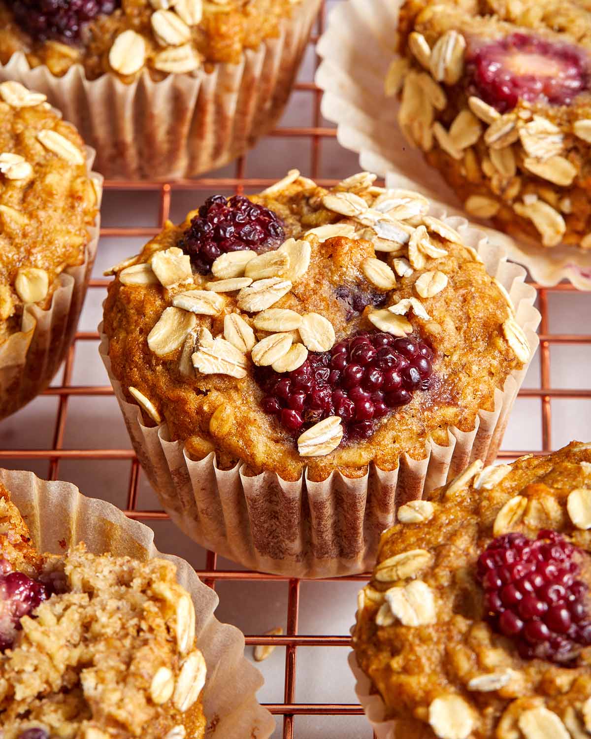 Close up view of a banana blackberry oatmeal muffin on a wire rack.