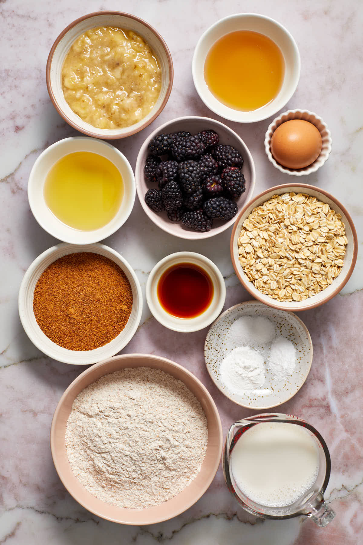 Ingredients to make banana blackberry oatmeal muffins arranged in individual bowls.