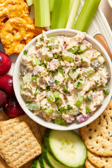 Tuna salad without mayo in a small bowl on a platter with crackers and veggies.