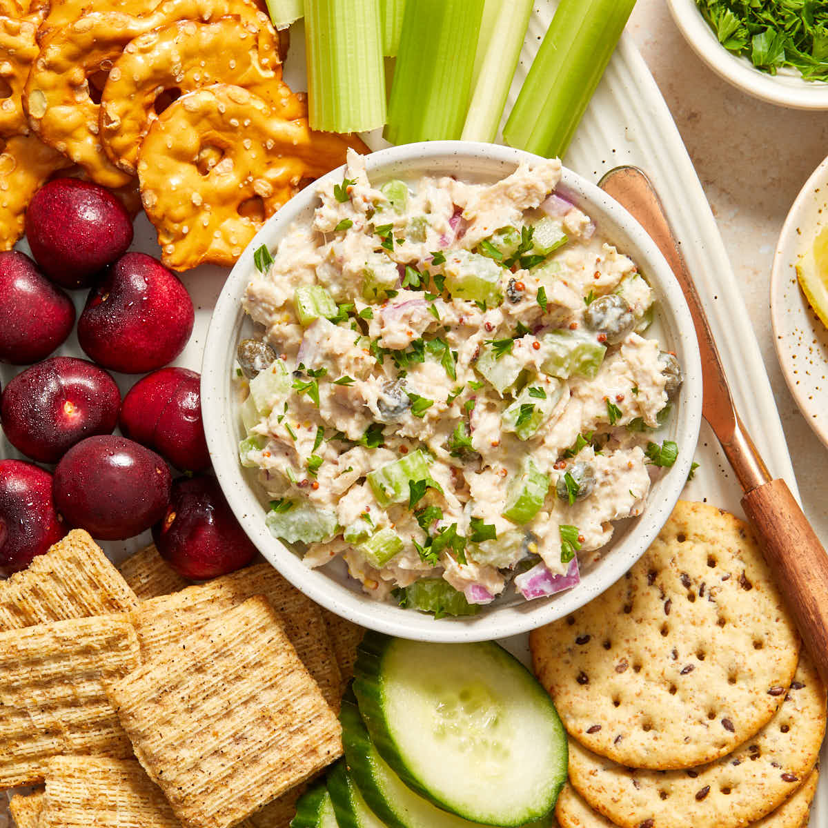 Tuna salad without mayo in a small bowl on a platter with crackers and veggies.