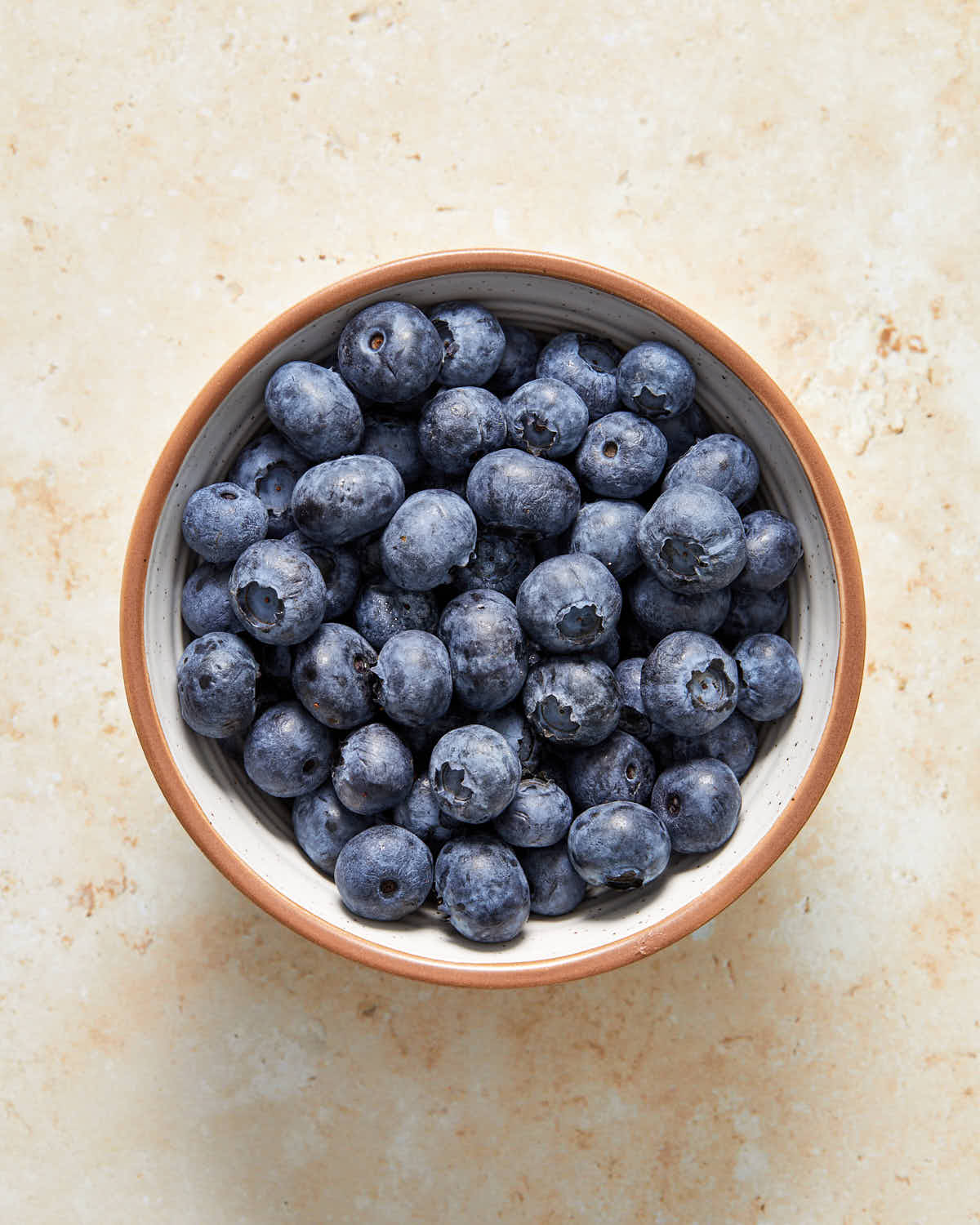 Overhead view of fresh blueberries in a white bowl.