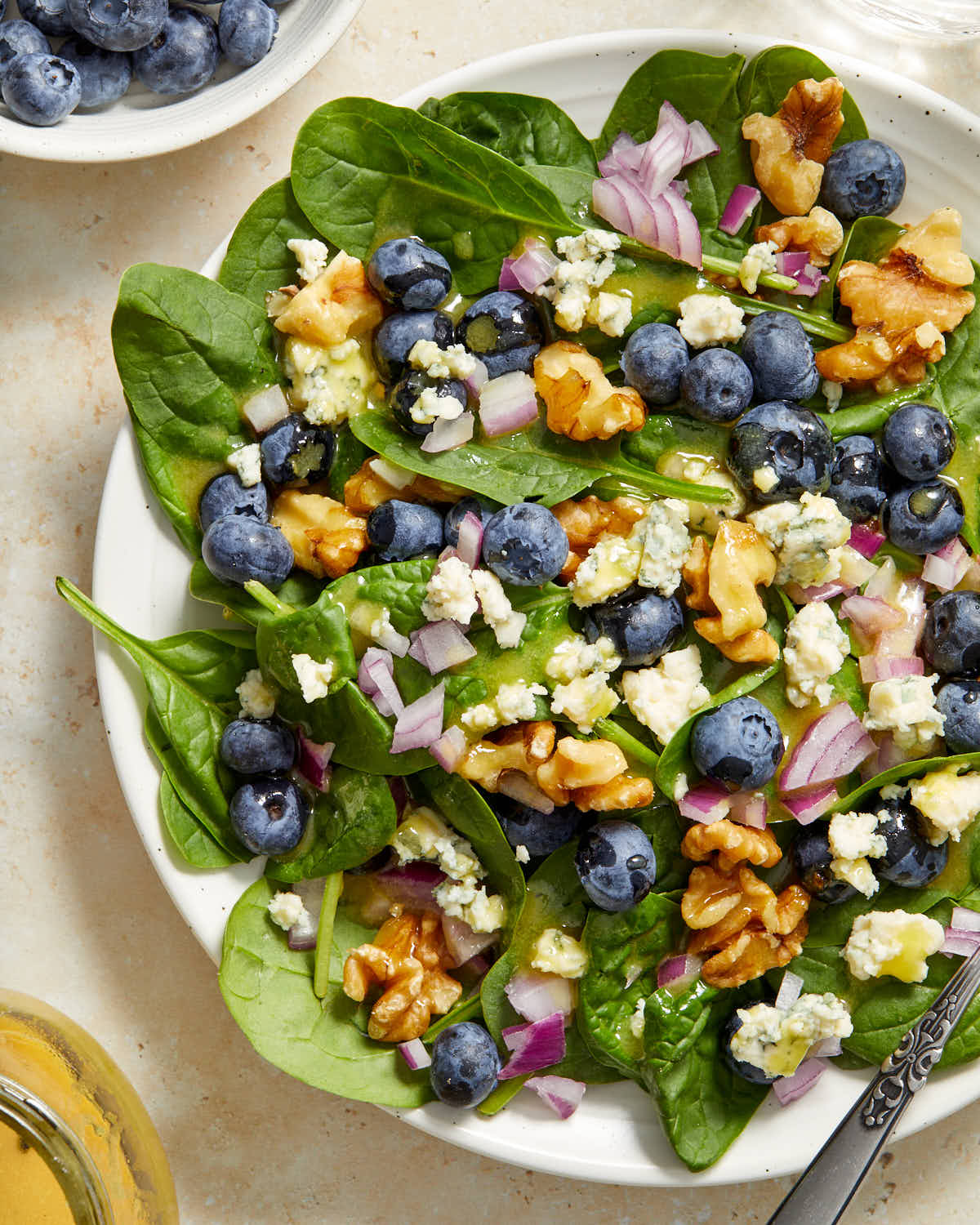 Close up view of spinach blueberry salad on a white plate.