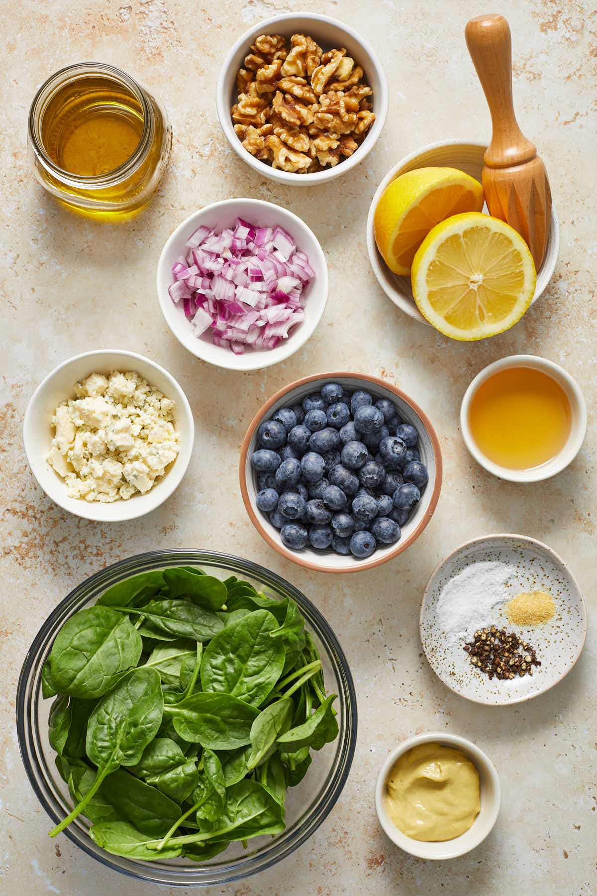 Ingredients to make blueberry spinach salad arranged in individual bowls.