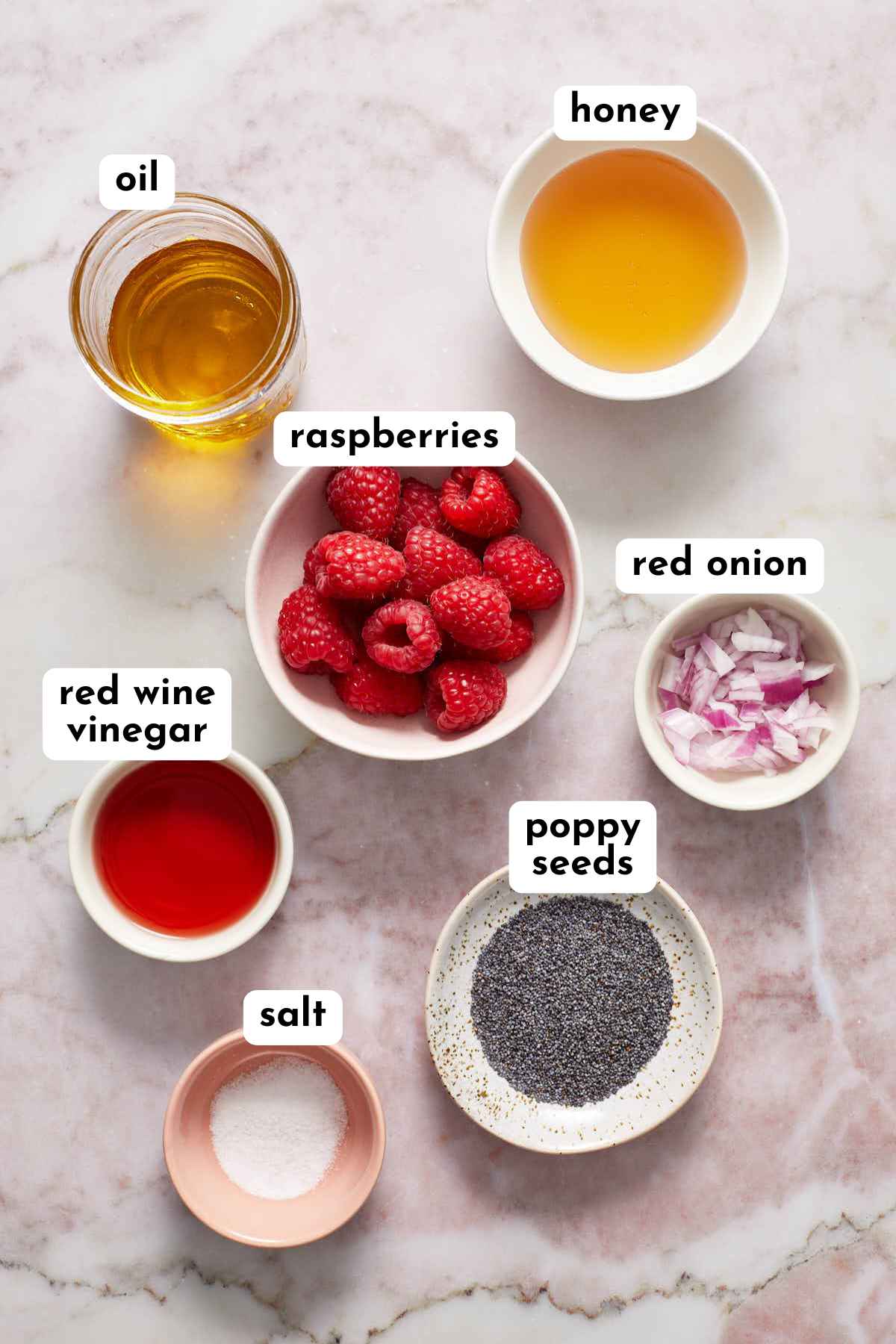 Ingredients to make raspberry poppy seed dressing arranged individually and labeled.