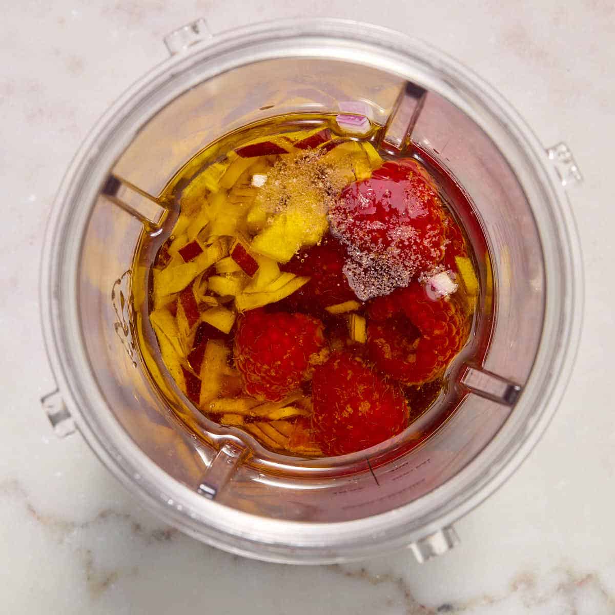 Ingredients to make the raspberry dressing in a blender cup, except the poppy seeds.