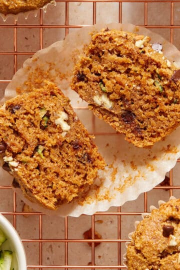 An almond flour zucchini muffin cut in half on a parchment paper wrapper.
