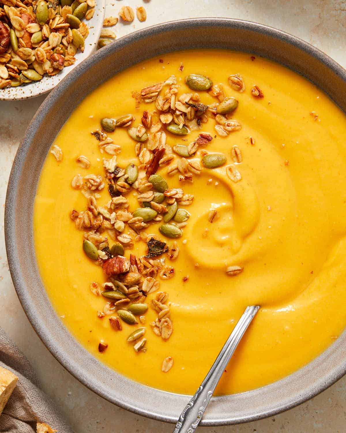 Close up of carrot butternut squash soup in a bowl and topped with savory granola.
