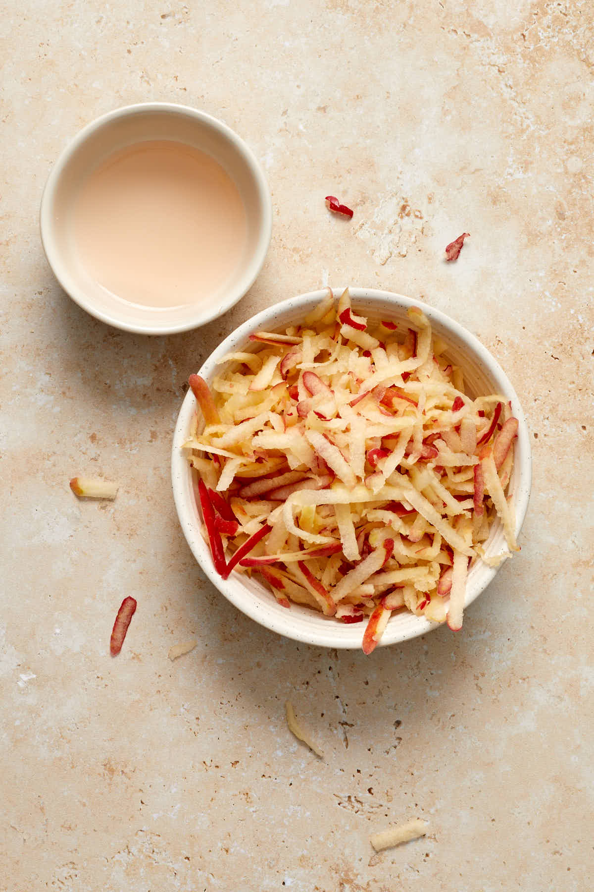Grated apple in a small dish with apple juice squeezed out in a side dish.