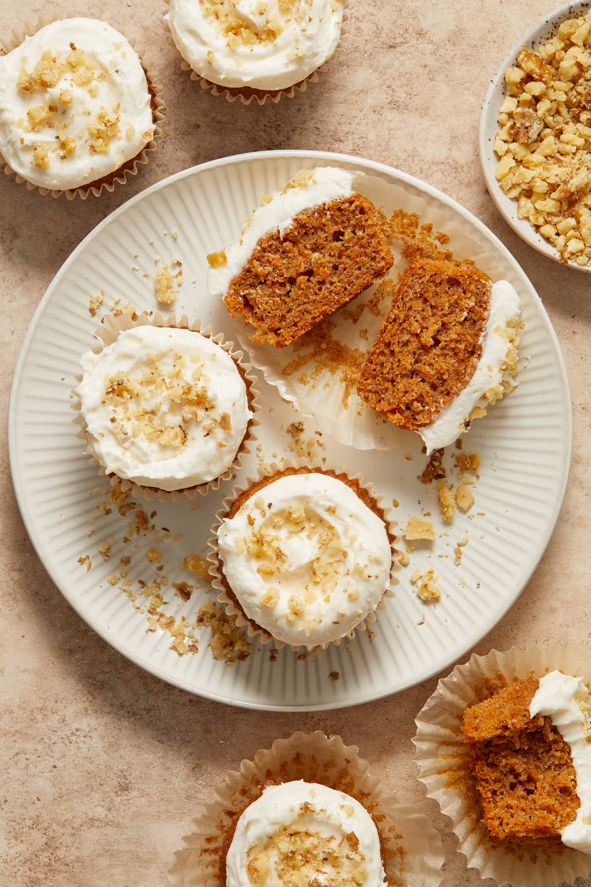 Carrot cupcakes arranged on a plate with one cut in half.