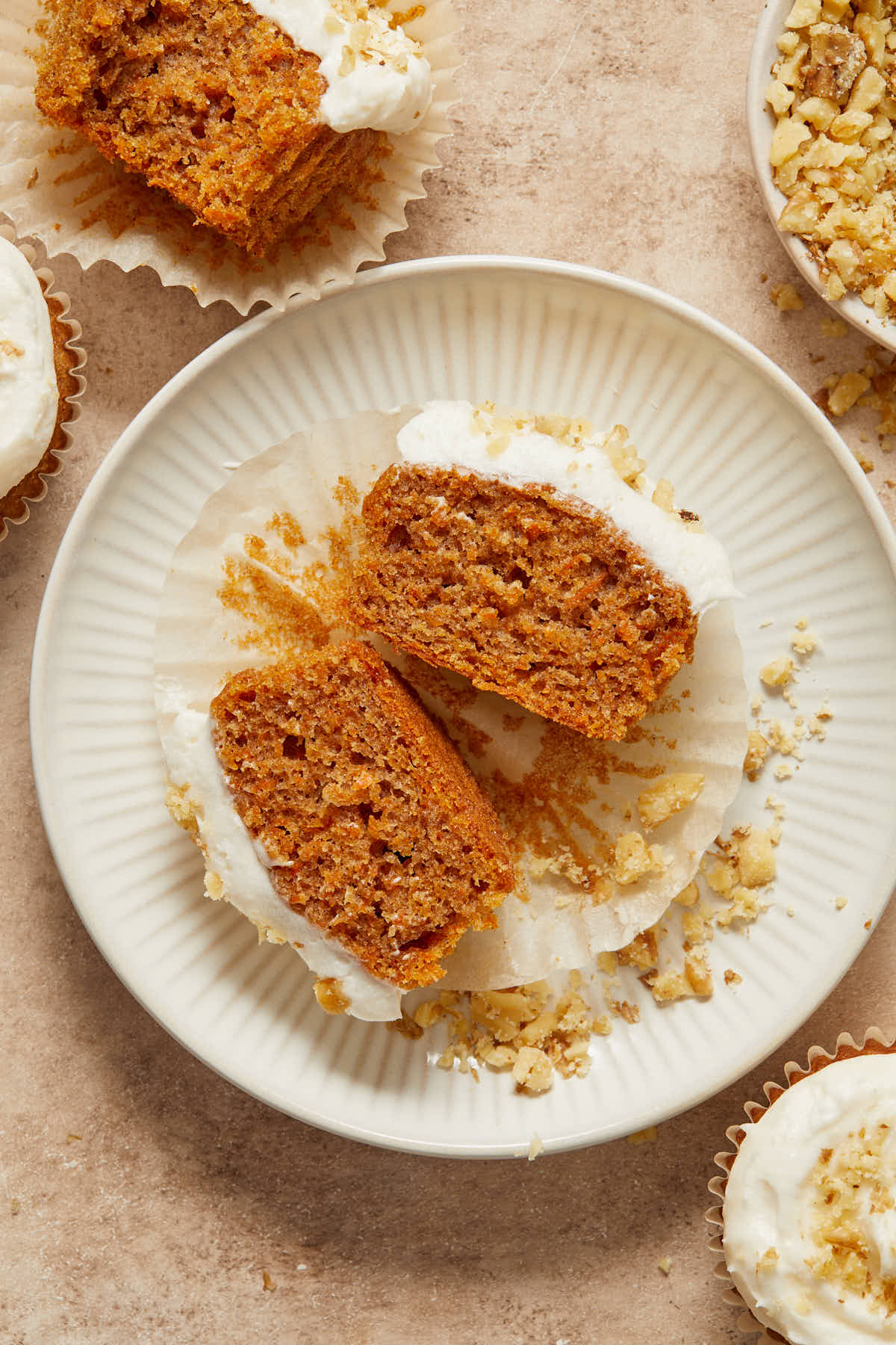 Close up of a carrot cake cupcake cut in half on a plate.