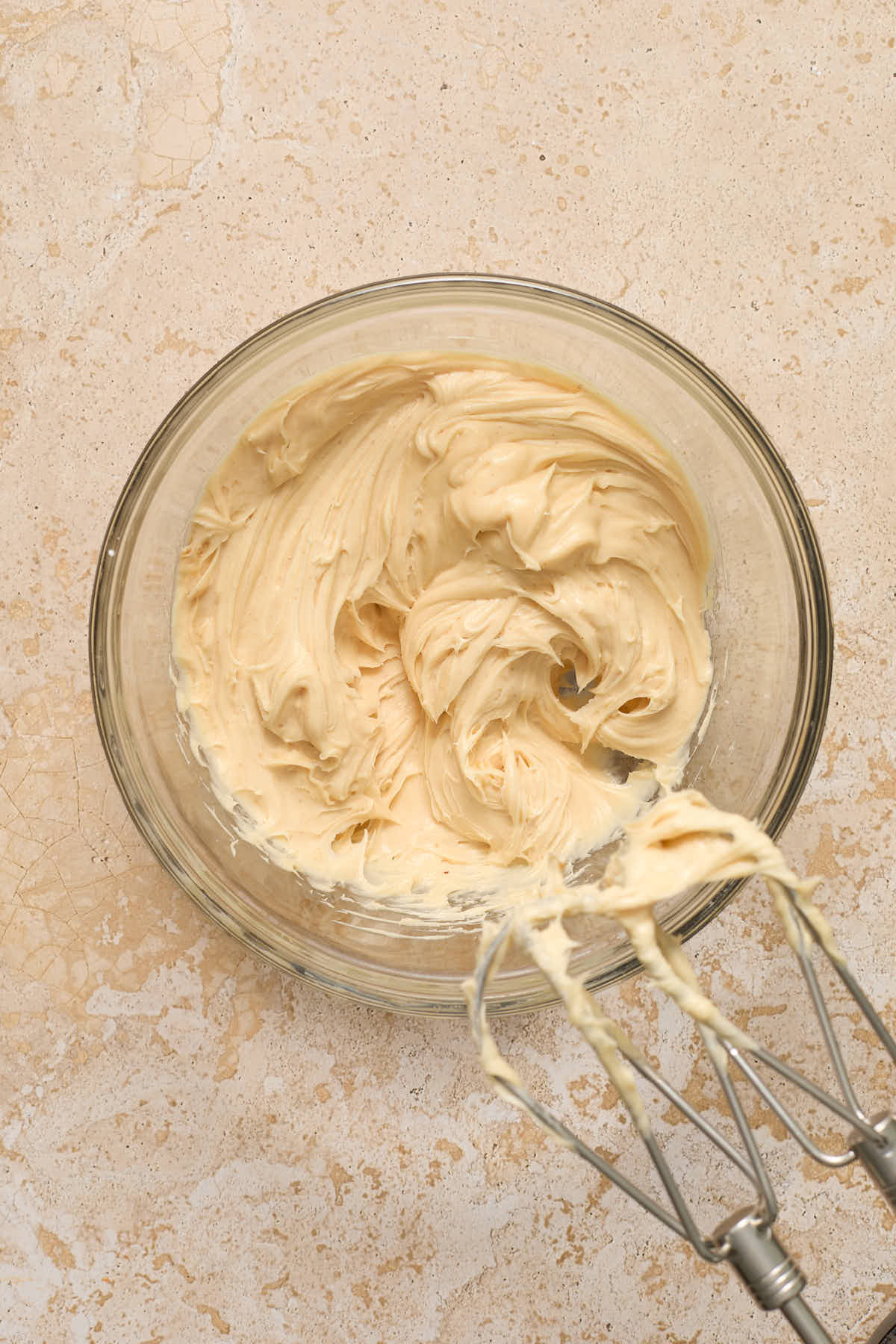 Peanut butter cream cheese frosting mixed together in a glass bowl.