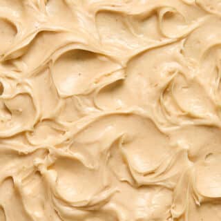 Close up view of peanut butter cream cheese frosting swirled on a cake.