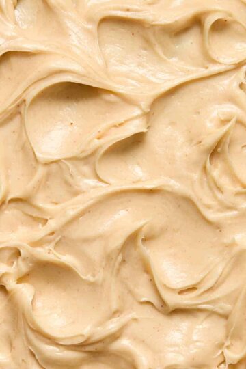 Close up view of peanut butter cream cheese frosting swirled on a cake.