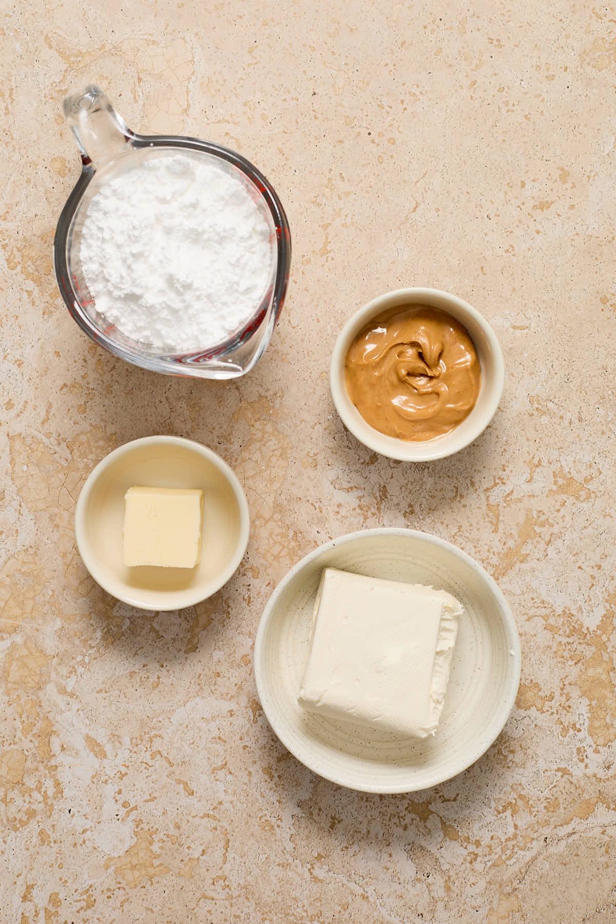 Ingredients to make peanut butter cream cheese frosting arranged in individual bowls.
