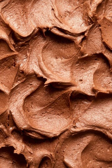 Close up view of swoops and swirls of chocolate peanut butter frosting on top of a cake.