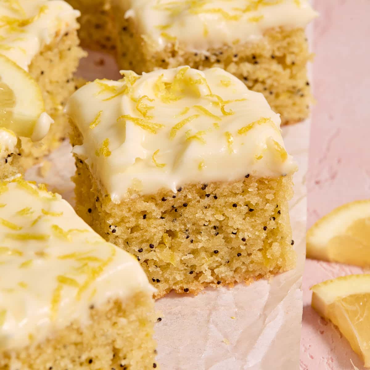 Pieces of almond flour lemon poppy seed cake arranged on parchment paper.