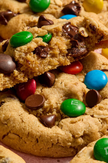Close up view of half of a monster cookie exposing the melted chocolate chips and crunchy M&Ms inside.