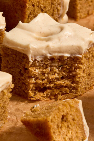 Piece of almond flour pumpkin cake topped with cream cheese frosting and a forkful removed.
