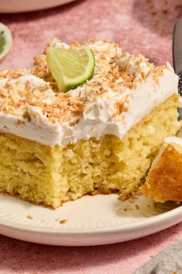 Piece of almond flour coconut lime cake on a plate with a forkful removed.