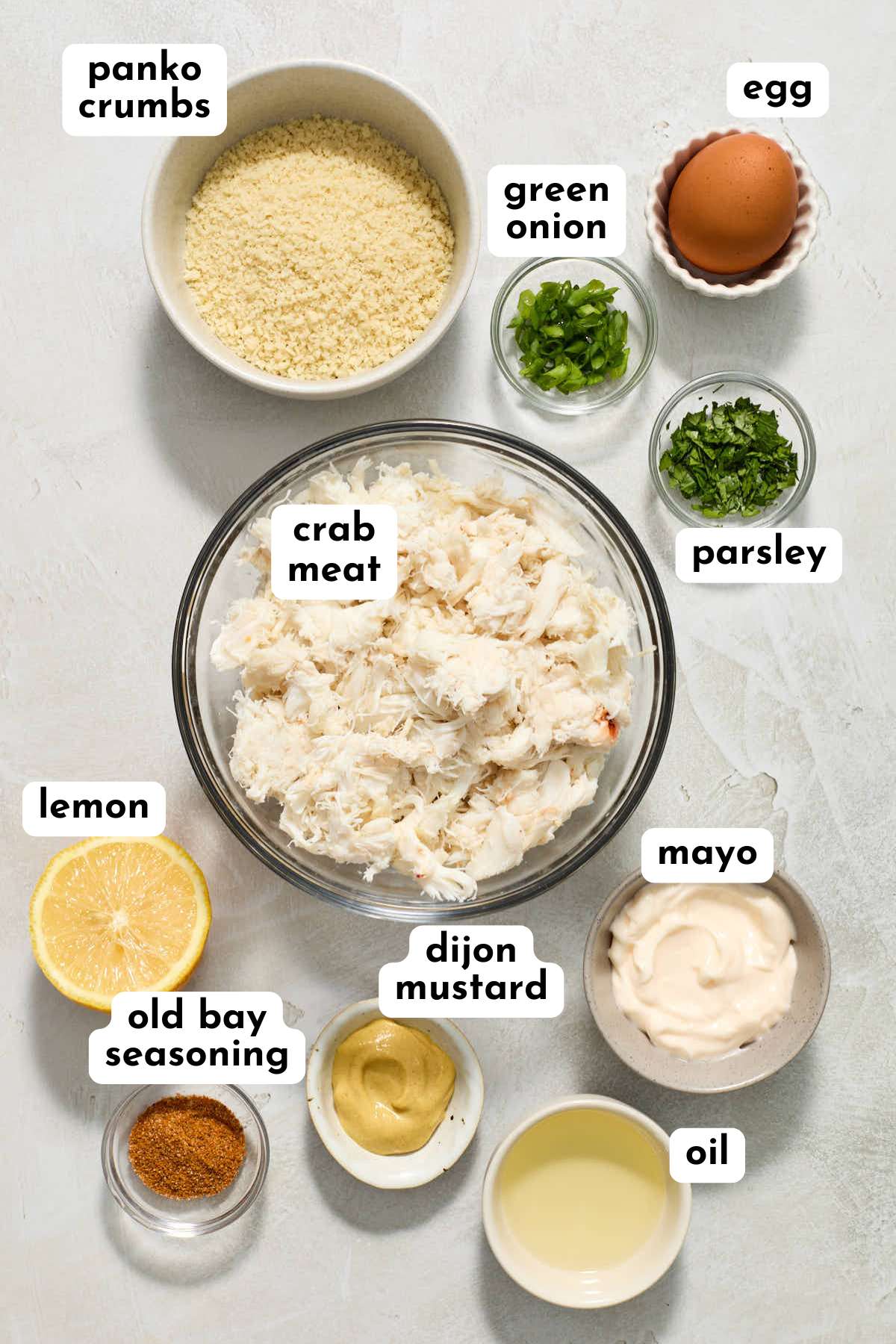 Ingredients for making crab cakes arranged individually and labeled.