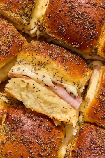 Close up of air fryer ham and cheese sliders with one turned on its side to show the ham and cheese filling.