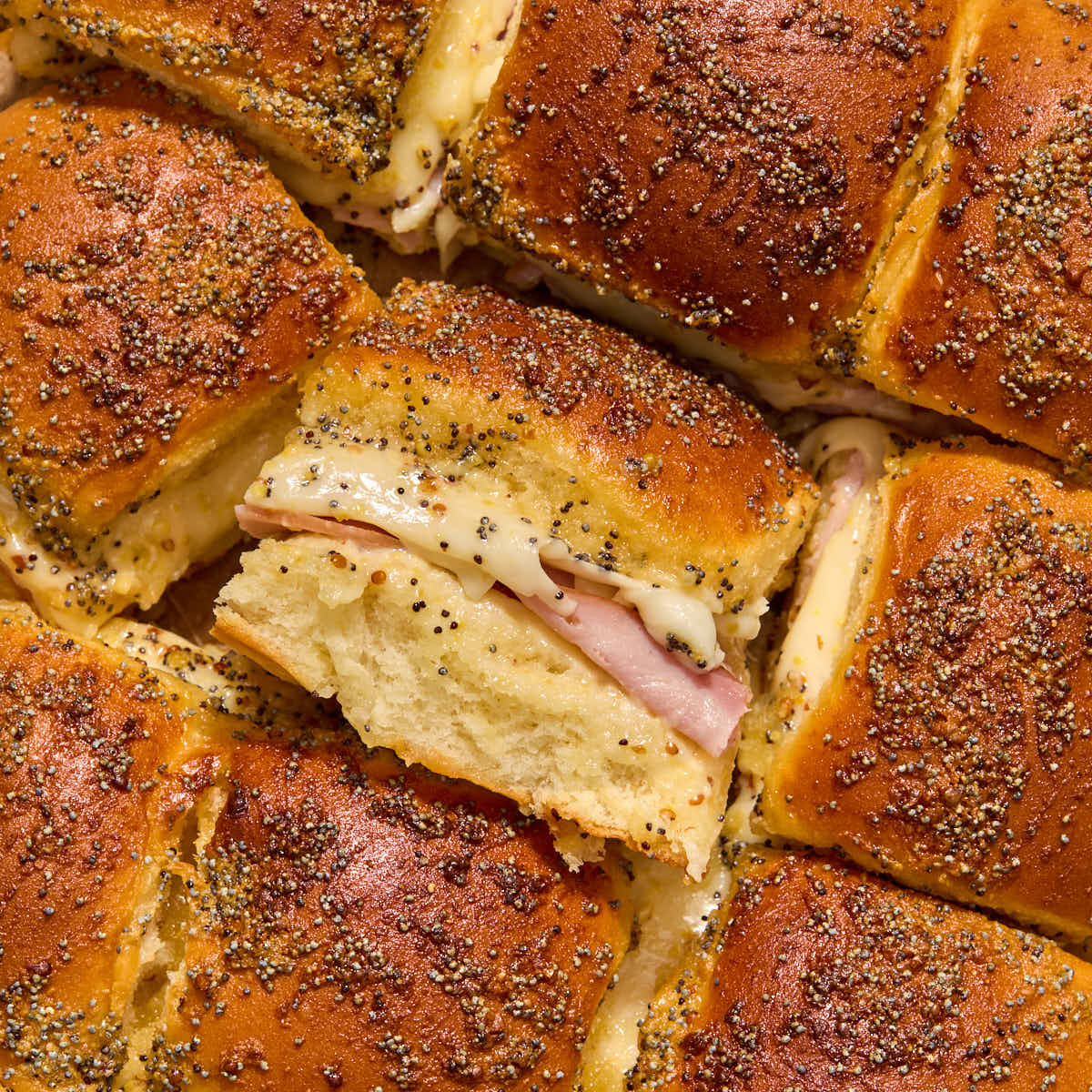 Close up of air fryer ham and cheese sliders with one turned on its side to show the ham and cheese filling.