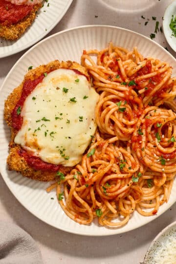 Air fryer chicken parmesan served on plates with spaghetti and marinara sauce.