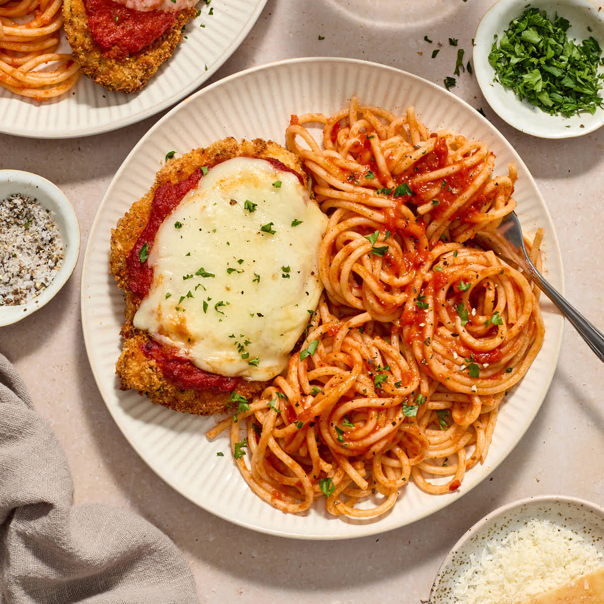 Air fryer chicken parmesan served on plates with spaghetti and marinara sauce.