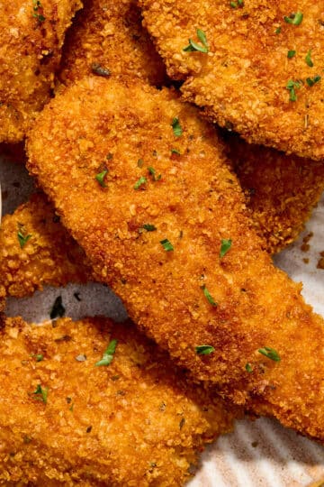 Close up view of air fryer cornflake chicken strips on a plate.