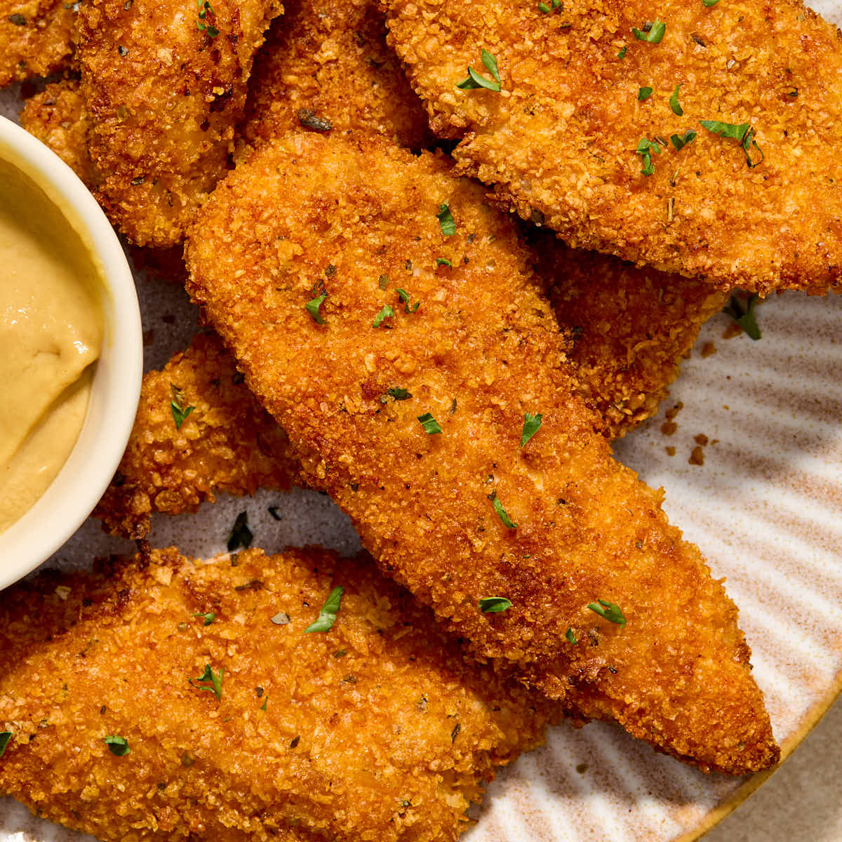 Close up view of air fryer cornflake chicken strips on a plate.