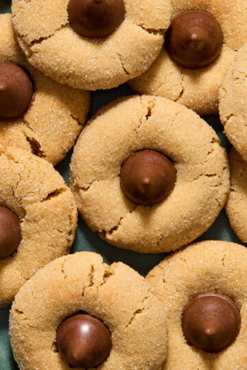 Overhead view of almond flour peanut butter blossoms arranged on a green plate.