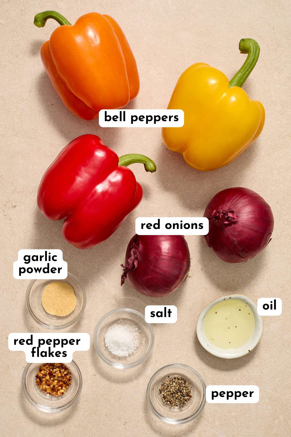 Ingredients to make air fryer peppers and onions arranged individually and labeled.
