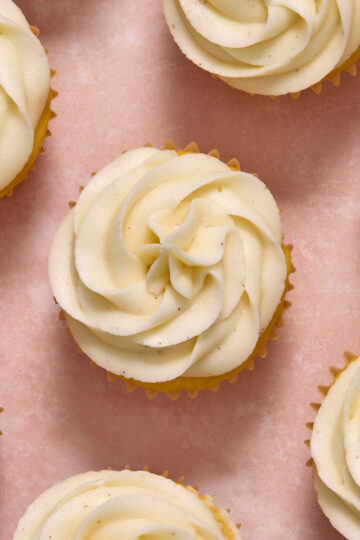 Overhead view of vanilla bean sour cream frosting piped onto cupcakes.