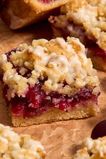 Close up side view of almond flour cherry pie bars arranged on brown parchment paper.