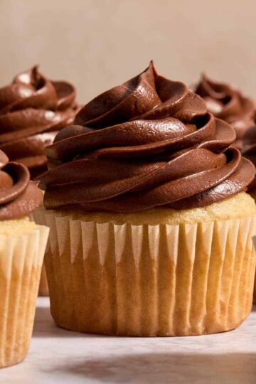 Side view of chocolate sour cream frosting piped on top of cupcakes.