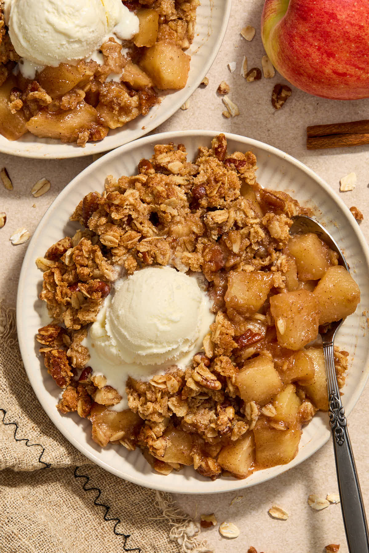 Apple crisp on a plate with vanilla ice cream on top.