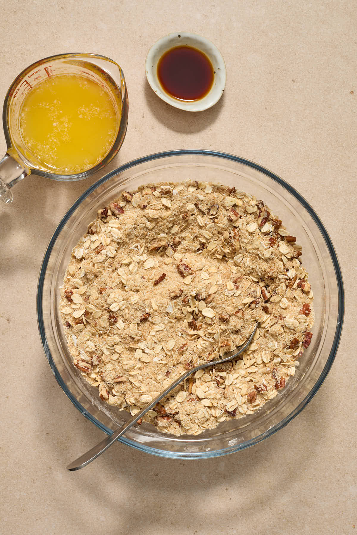 Dry crisp ingredients stirred together in a glass bowl with melted butter and vanilla on the side.