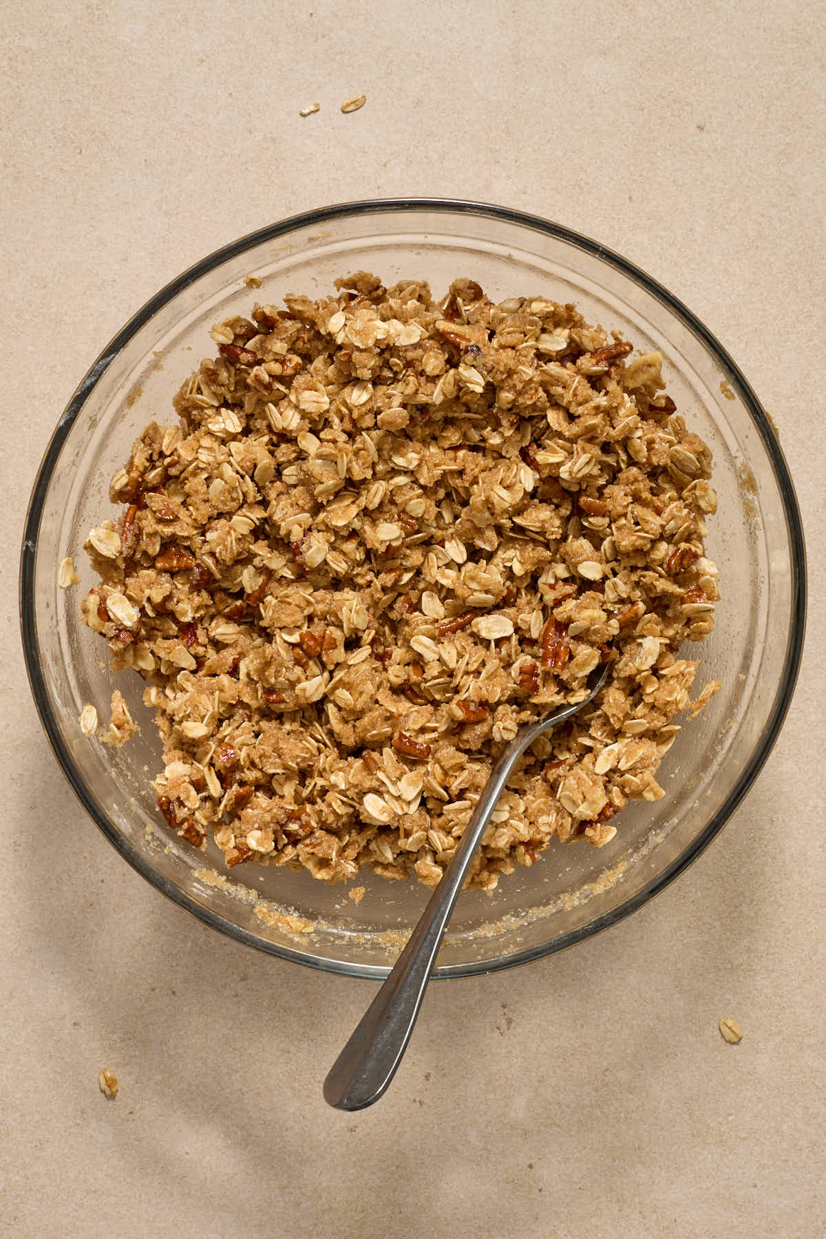 Crisp topping mixed together in a glass bowl with a fork.
