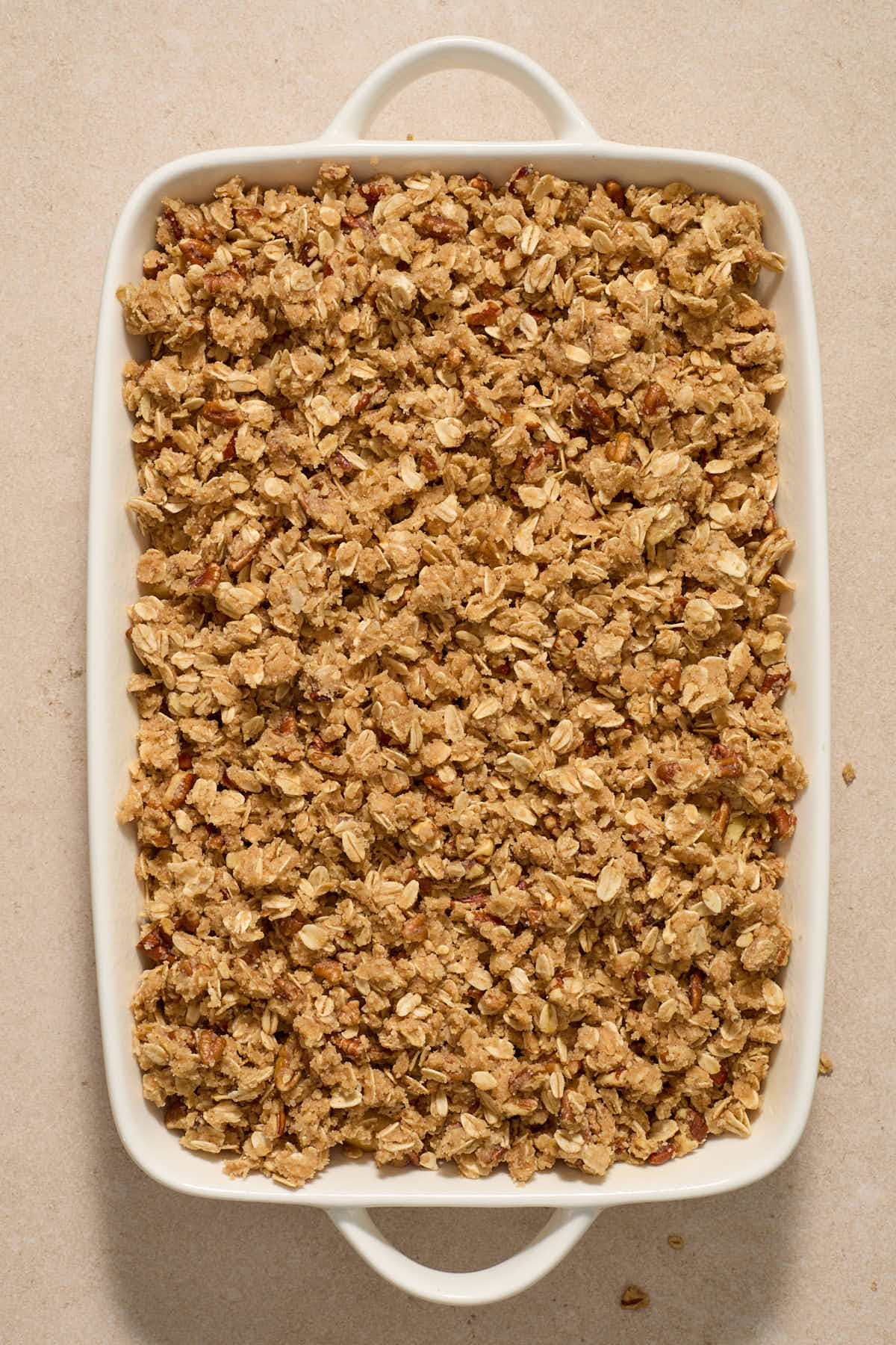 Crisp topping layered on top of apples in baking dish.