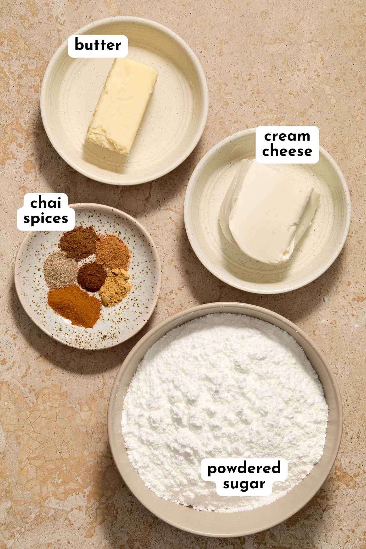 Ingredients to make chai spice cream cheese frosting arranged individually and labeled.