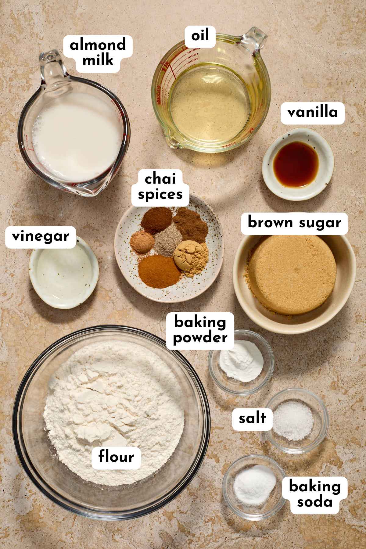 Ingredients to make a chai spice cake arranged in individual bowls and labeled.