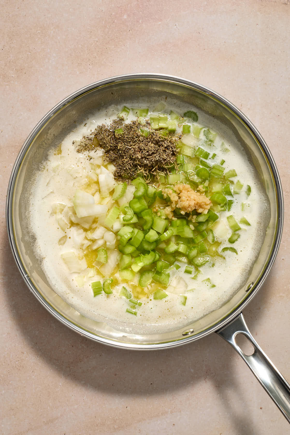 Celery, onion, garlic and herbs added to melted butter in a skillet.