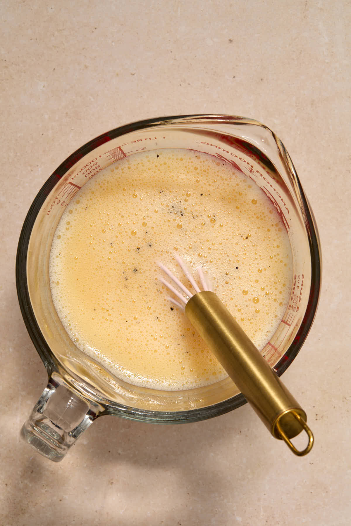 Eggs, broth, salt and pepper whisked together in a glass measuring cup.