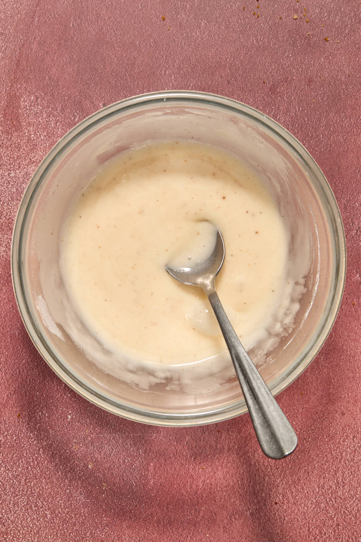 Eggnog glaze stirred together in a small bowl with a spoon.
