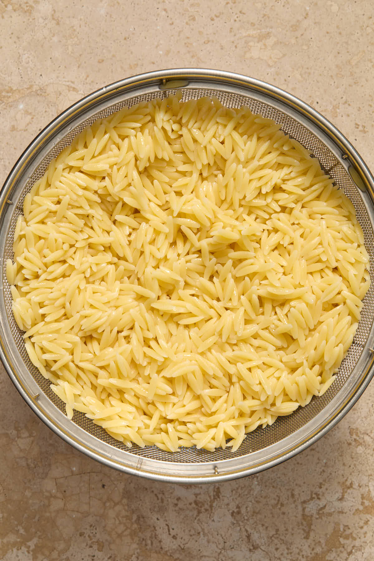 Cooked orzo in a metal colander.