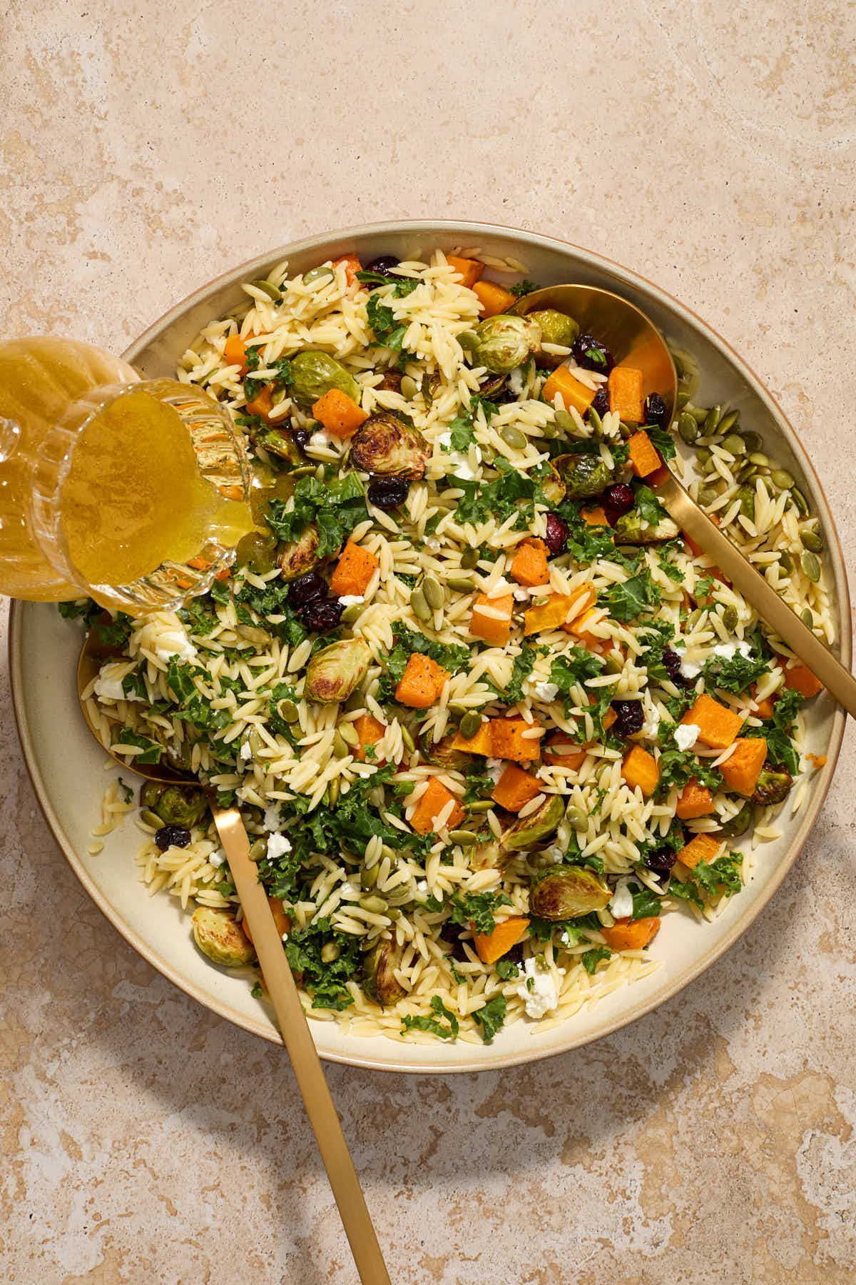 Salad ingredients tossed together in a bowl with the vinaigrette being poured over top.