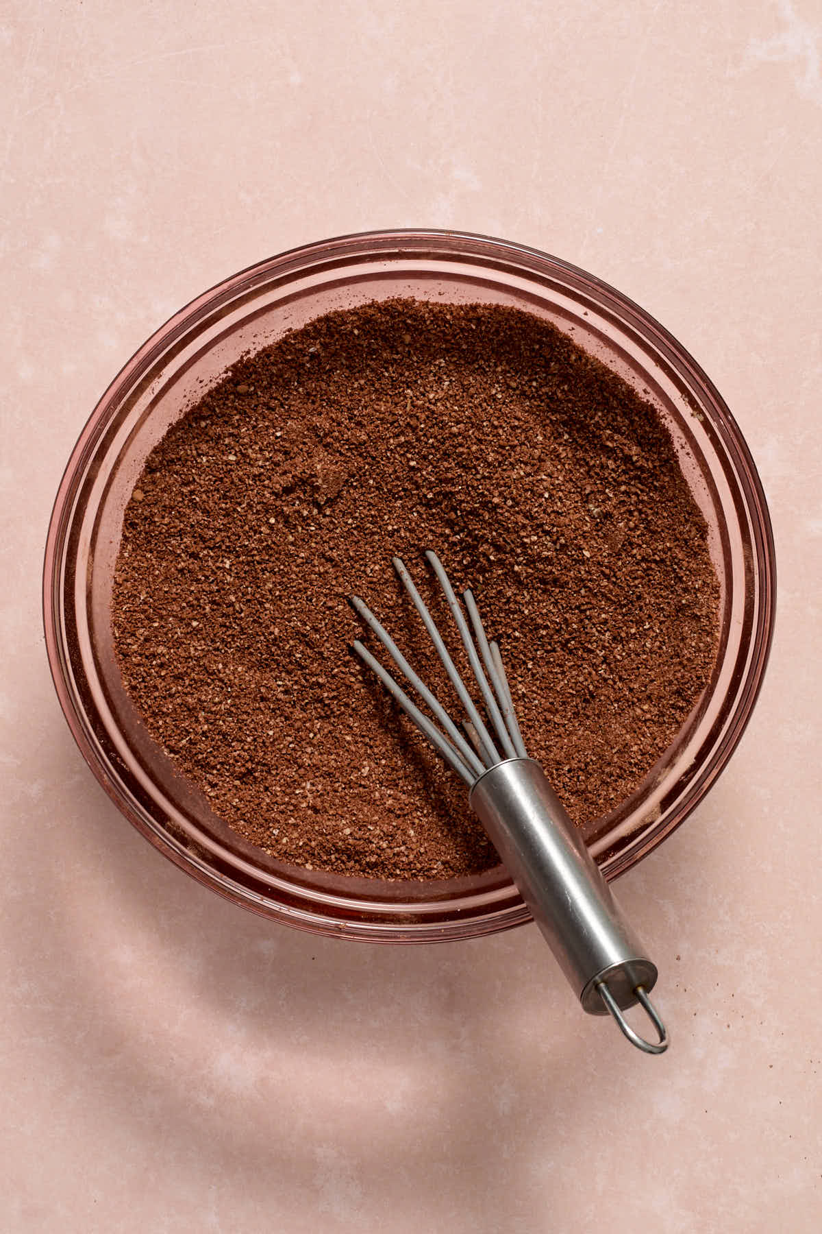 Cocoa and other dry ingredients whisked together in a glass bowl.