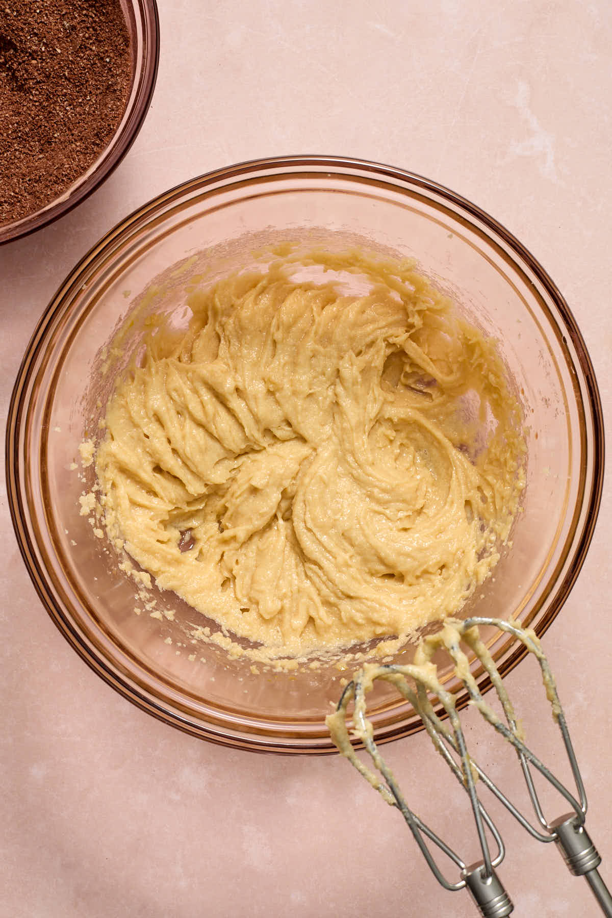 Wet ingredients mixed together in a glass bowl with a bowl of dry ingredients on the side.