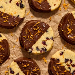 Overhead view of almond flour orange cranberry cookies dipped in chocolate and topped with orange zest and flaky sea salt.
