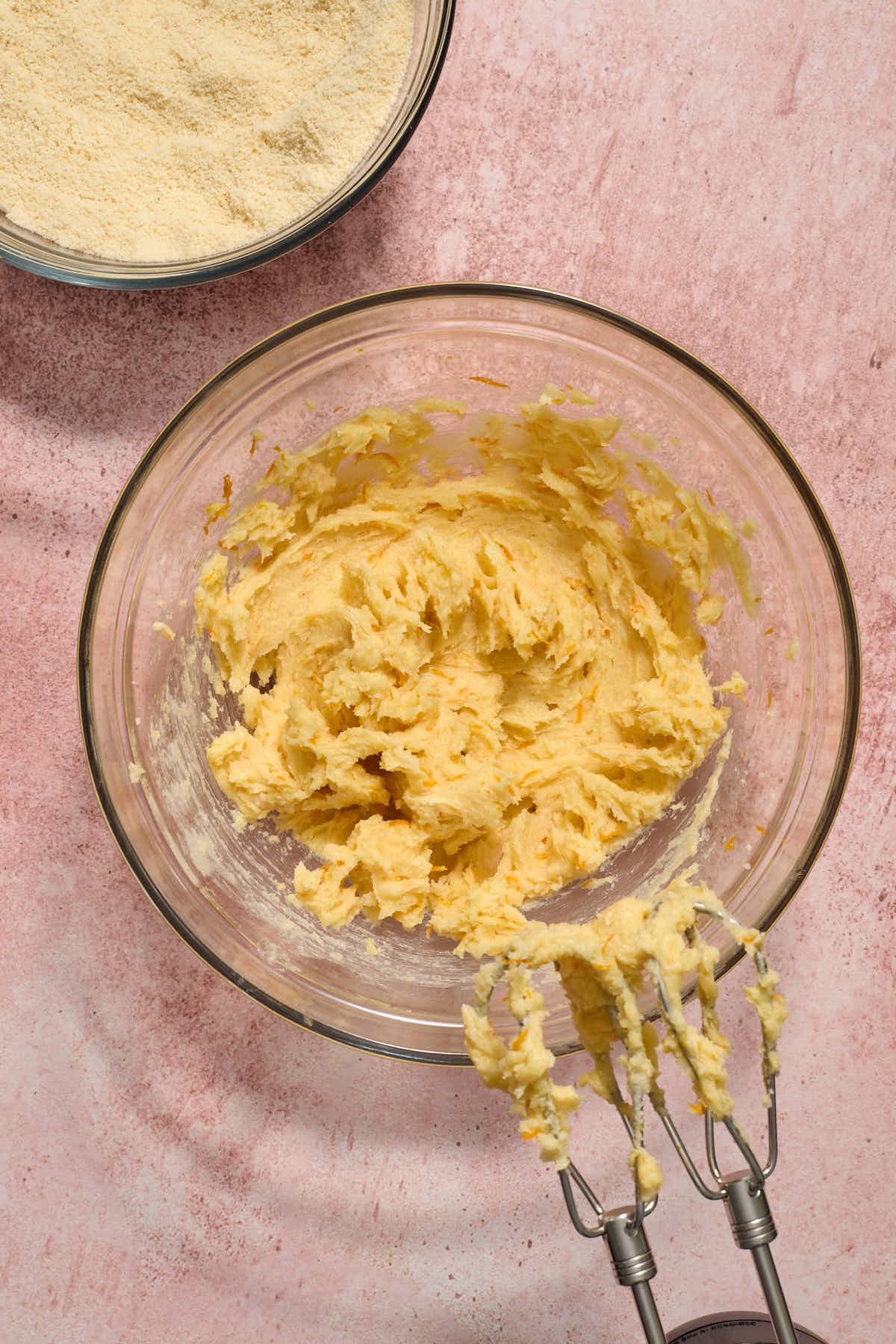 Orange juice and zest mixed into the butter mixture with the dry mixture in a bowl to the side.